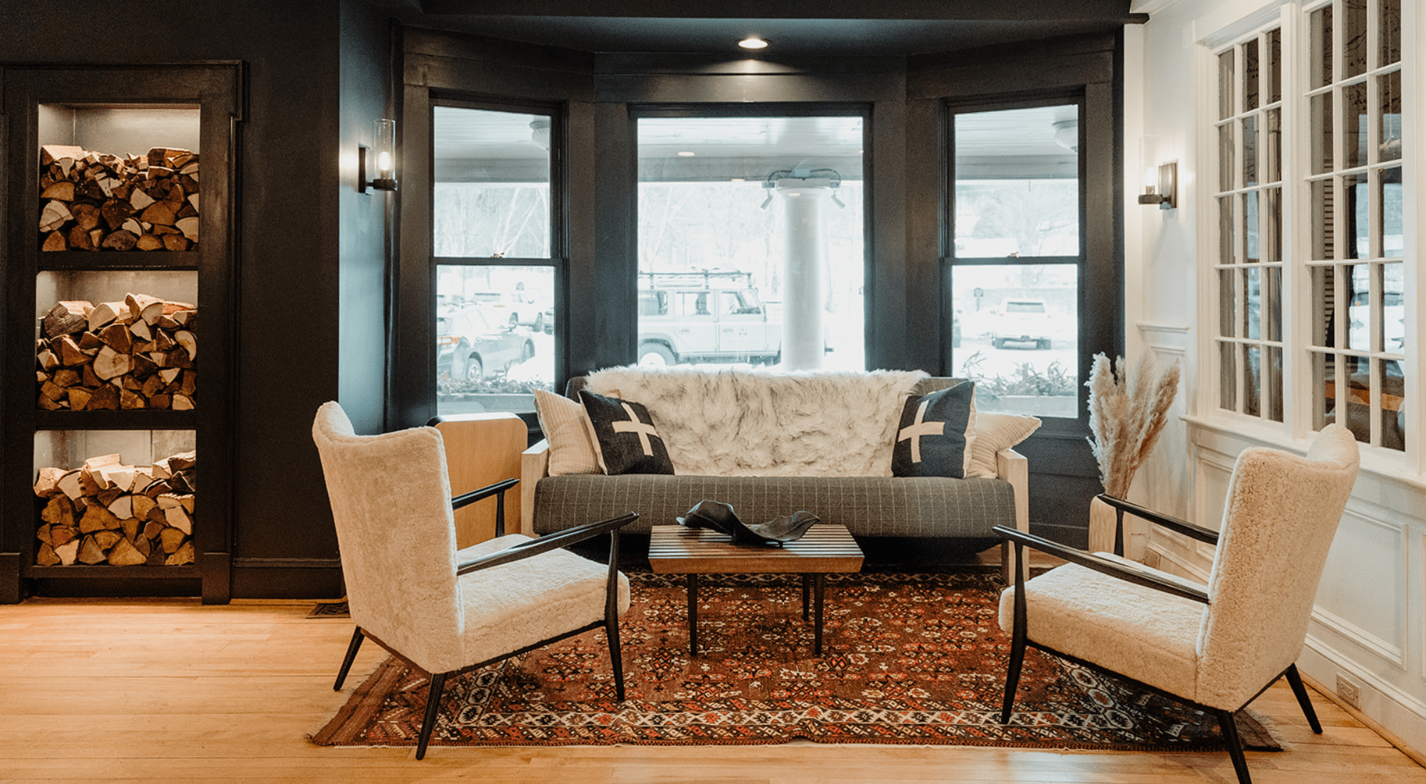 Two chairs, coffee table, firewood stack and a couch at the Wentworth.