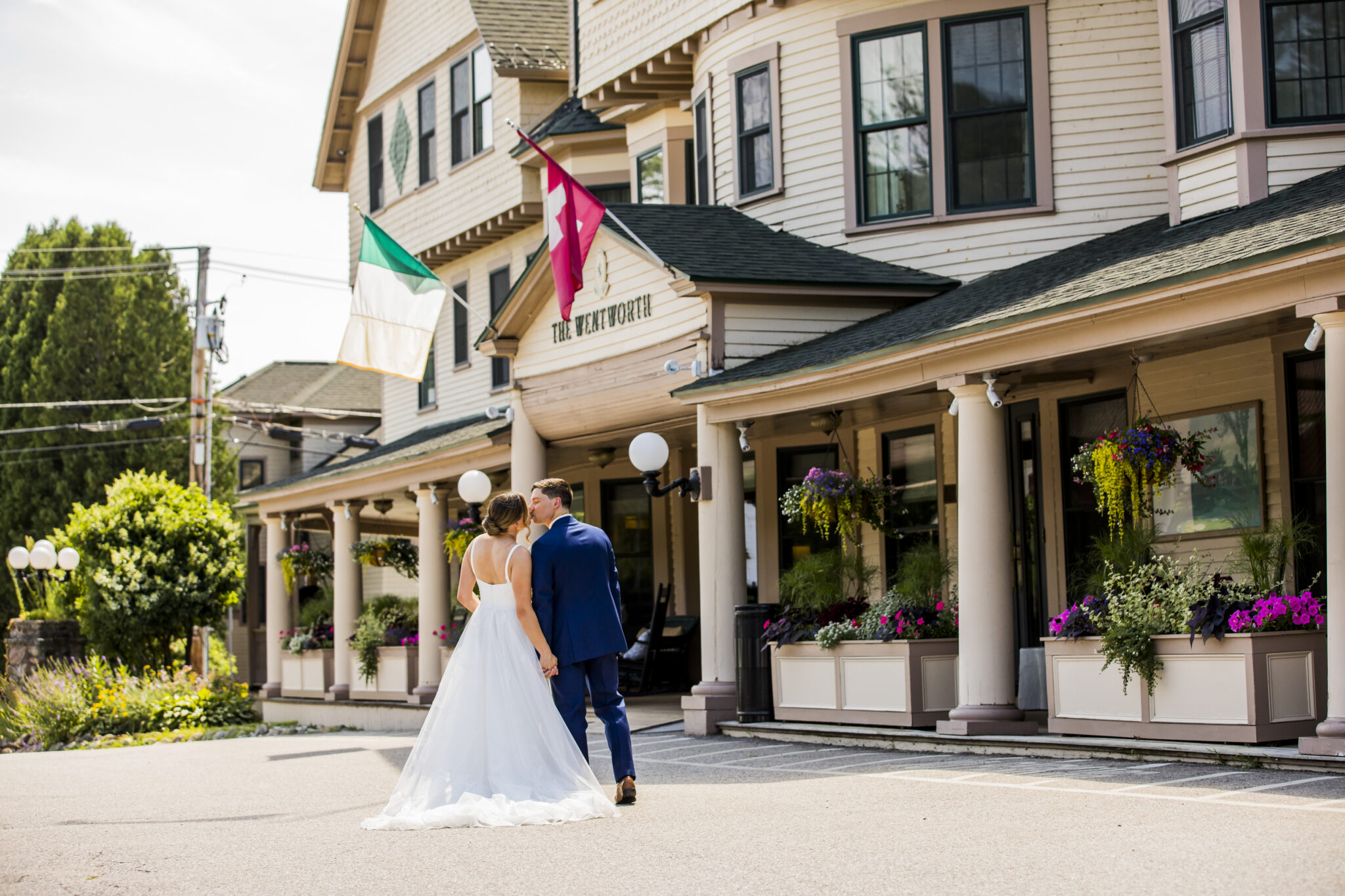 A couple in wedding attire walking outside a building with a sign reading "THE WHEATH".