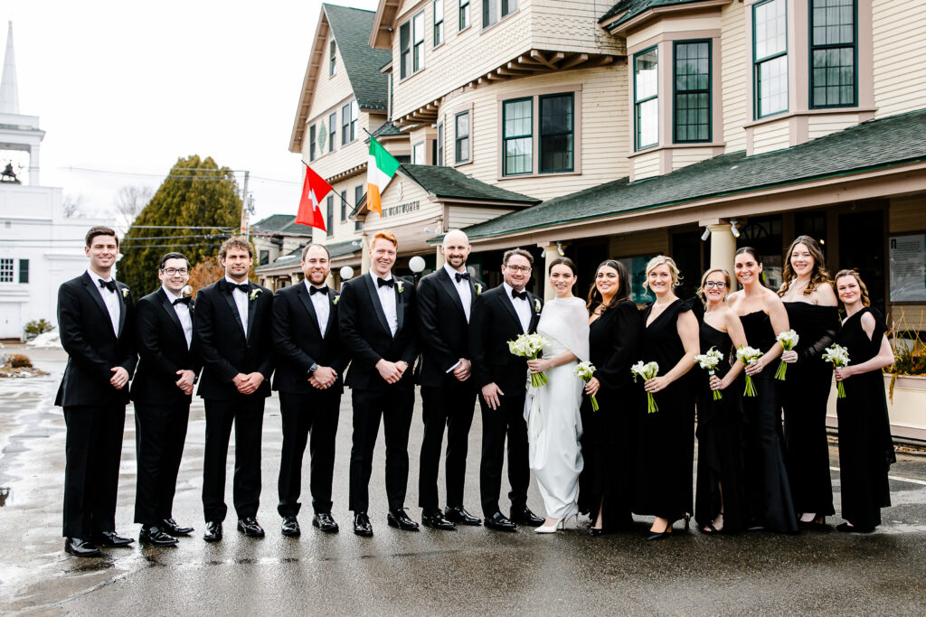A group of 10 people, including a bride and groom, standing in front of a building.