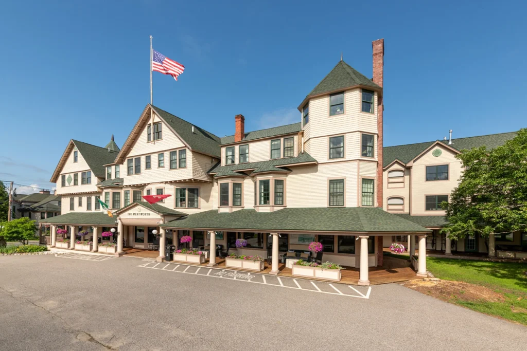 large white building with green roof and American flag on pole. building has many windows and a covered entrance with columns.